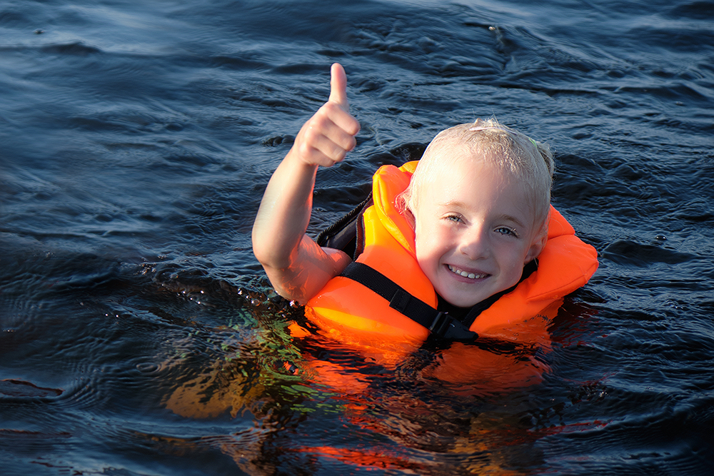 A child with a lifevest giving you a thumbs-up