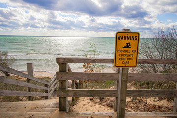 Lake Michigan with a fence border and a warning for possible rip currents, swim with care